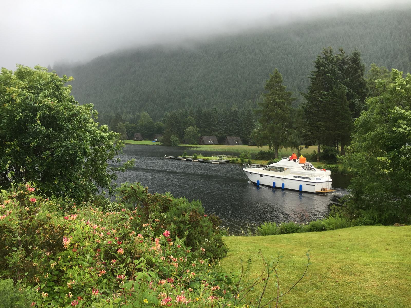 A boat on a peaceful Highland loch surrounded by forest